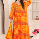 A woman modeling a orange and gold long-sleeve kaftan with Aari work with gold beads.