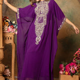 A woman wearing a purple farasha kaftan with embroidered silver beads, posing in a floral backdrop.