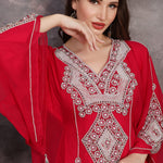 Woman wearing a red embroidered dress against a gray background