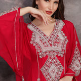Woman wearing a red embroidered dress against a gray background