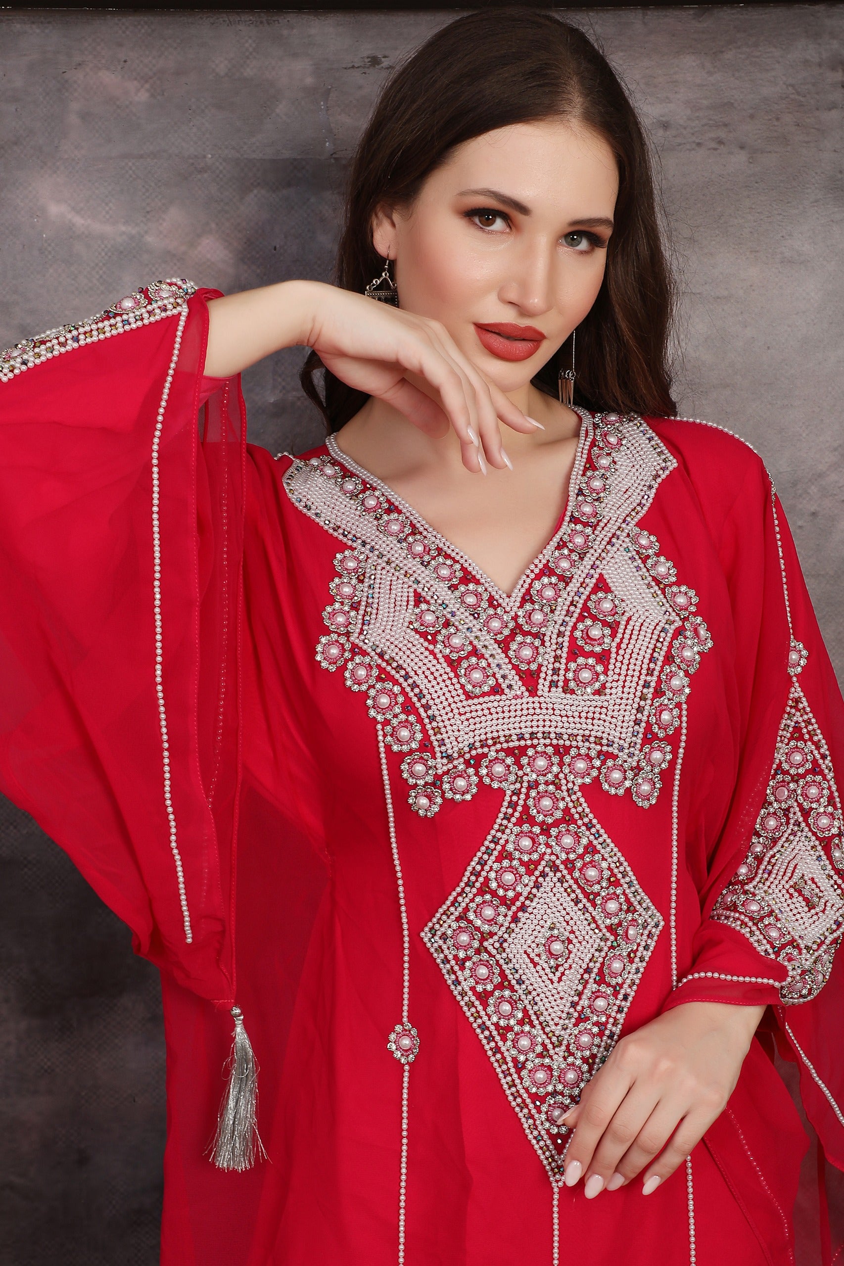 Woman wearing a red embroidered dress against a gray background