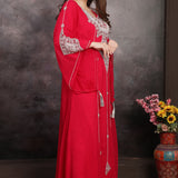 Woman in a red dress with silver embellishments standing against a dark background.