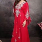 Woman in a red embroidered dress against a dark background