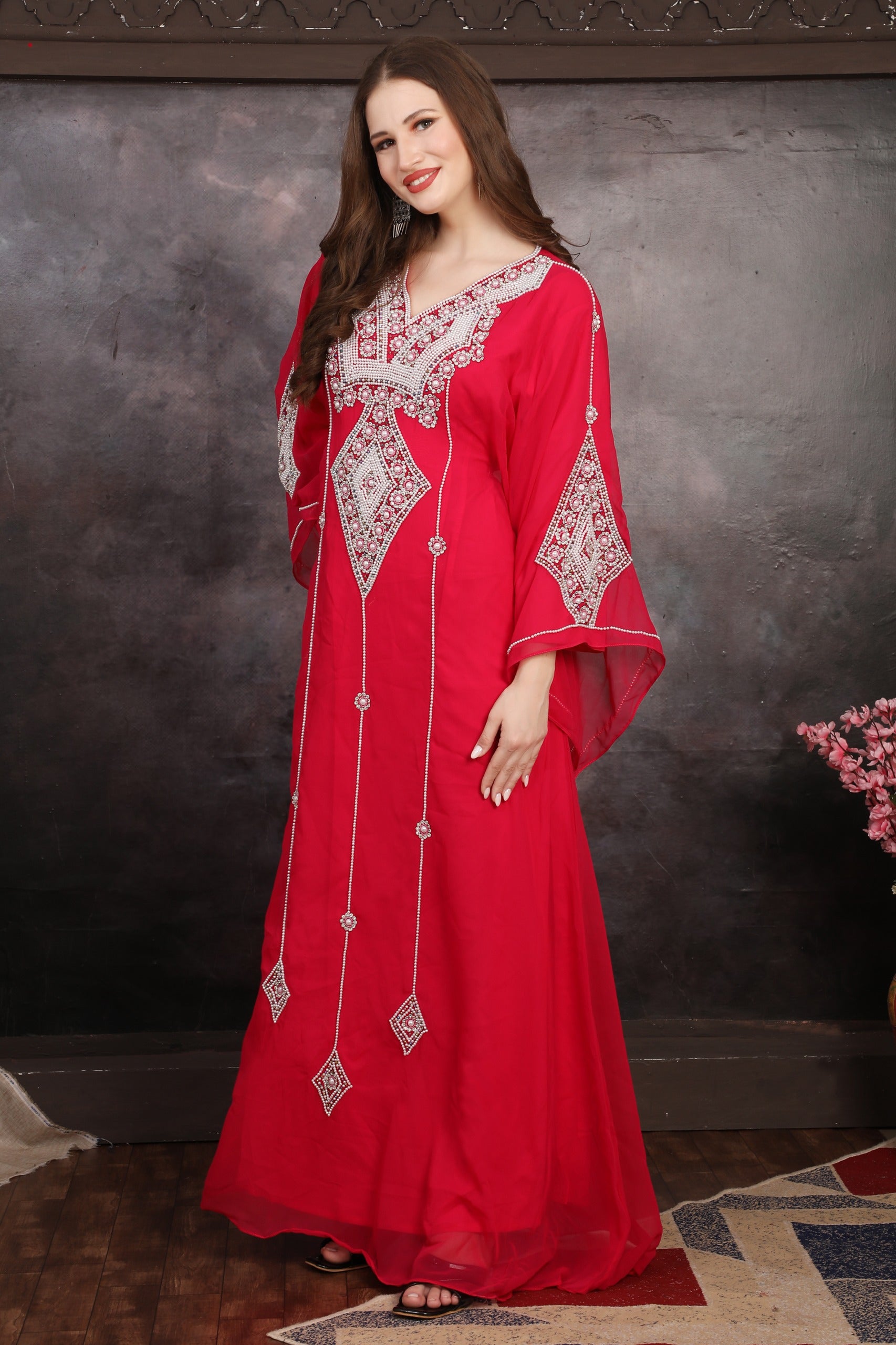 Woman in a red embroidered dress against a dark background
