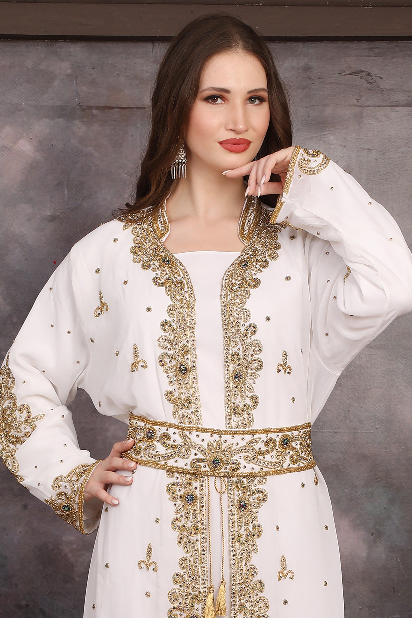 Close-up of Woman wearing a white dress with gold embroidery against a gray background
