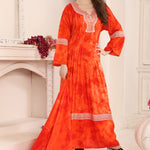A woman modeling a red cotton kaftan with Aari work with beads, standing in a room with a white fireplace.