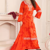 A woman modeling a red cotton kaftan with Aari work with beads, standing in a room with a white fireplace.