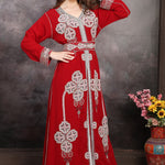 Woman in a red embroidered dress with a vase of flowers on a wooden table.
