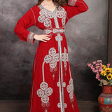 Woman in a red embroidered dress with a vase of flowers on a wooden table.