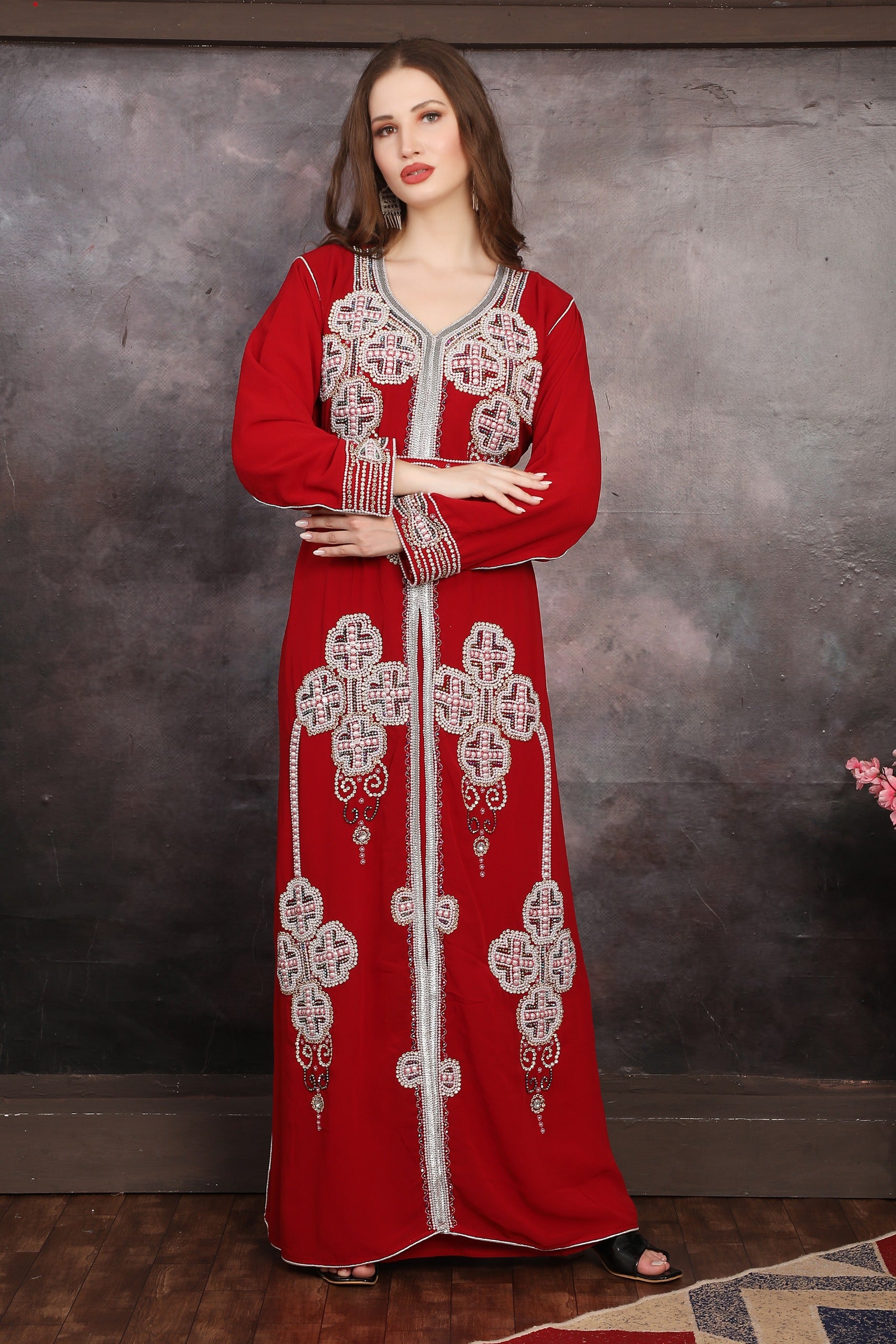 A woman wearing a red Moroccan caftan with silver and multicolor bead embellishments.