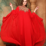 A woman wearing a red, traditional, embellished kaftan with a belt, posing in a grand setting with decorative walls and ceiling.