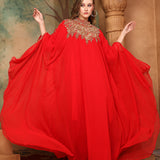 A woman wearing a red, traditional, embellished kaftan with a belt, posing in a grand setting with decorative walls and ceiling.