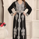 A woman wearing a black and silver Moroccan caftan with floral bead embroidery.