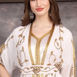 Close-up of hand-embellished gold beads on Moroccan georgette caftan fabric.